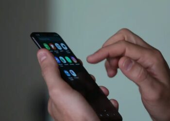 Usuário utilizando o dedo para navegar na tela de um smartphone com diversos ícones de aplicativos, simbolizando o acesso a plataformas de apostas (BETs) e as novas restrições federais.