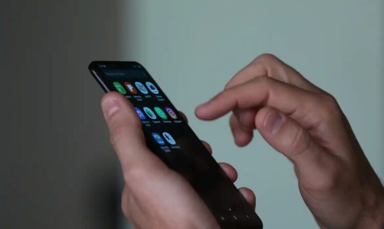 Usuário utilizando o dedo para navegar na tela de um smartphone com diversos ícones de aplicativos, simbolizando o acesso a plataformas de apostas (BETs) e as novas restrições federais.