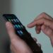 Usuário utilizando o dedo para navegar na tela de um smartphone com diversos ícones de aplicativos, simbolizando o acesso a plataformas de apostas (BETs) e as novas restrições federais.