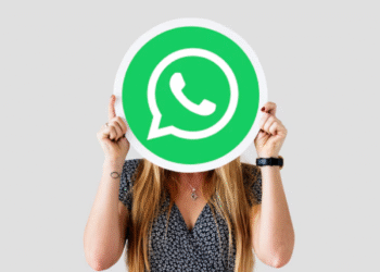 Mulher com cabelo longo segurando placa com símbolo verde do WhatsApp cobrindo o rosto