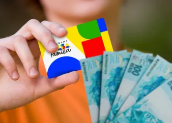 Mão segurando o cartão do Bolsa Família e notas de 100 reais, ilustrando locais e prazo de saque do benefício.