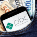 Pix agendado com sucesso! Veja quem recebe R$ 600,00 na próxima sexta (14) 11 Celular com logo do Pix no bolso de calça jeans junto a cédulas de reais.