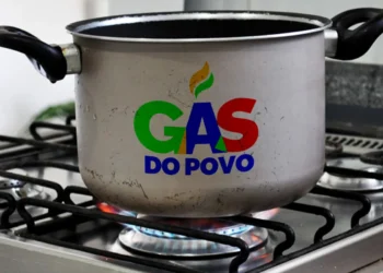 Panela cinza no fogão a gás aceso com a logo colorida "Gás do Povo". Símbolo de acesso facilitado a energia para famílias.