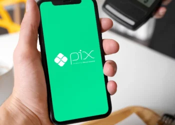 Mão segurando smartphone com a tela do aplicativo Pix aberta em fundo verde