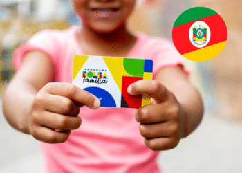 Criança segurando o cartão do Programa Bolsa Família, com a bandeira do Rio Grande do Sul ao fundo.