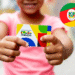 Criança segurando o cartão do Programa Bolsa Família, com a bandeira do Rio Grande do Sul ao fundo.