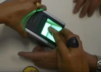 Técnico realizando biometria digital em equipamento do INSS durante procedimento de identificação.