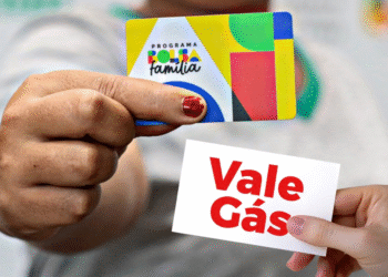 Pessoa segurando o cartão do Bolsa Família ao lado de outra mão com um cartão escrito “Vale Gás”.