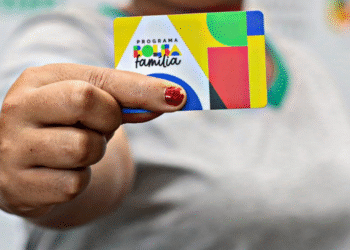 Bolsa Família de novembro: que horas o dinheiro cai no Caixa Tem nesta quinta (20)? 5 Pessoa segurando um cartão do programa Bolsa Família com design colorido.