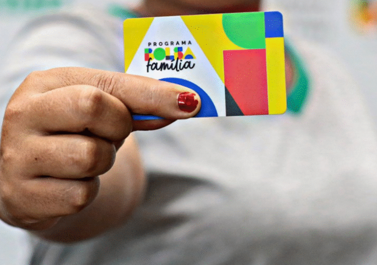 Pessoa segurando um cartão do programa Bolsa Família com design colorido.
