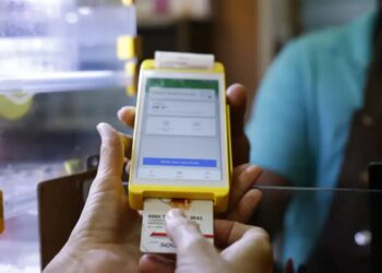 Pessoa inserindo cartão em dispositivo amarelo de pagamento digital com tela touch