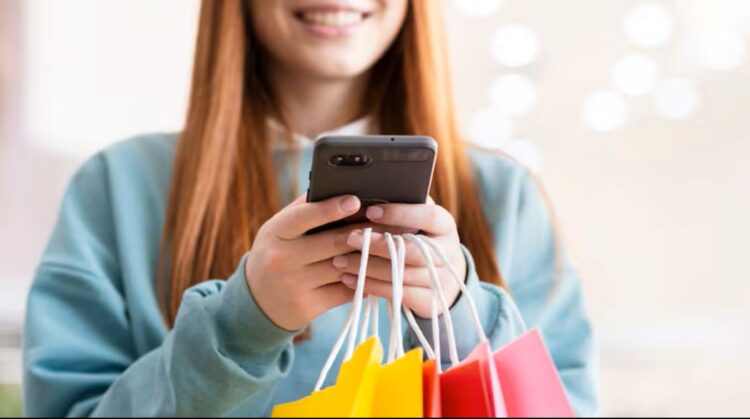 Mulher segurando sacolas coloridas e usando o celular, representando atenção aos golpes durante a Black Friday.