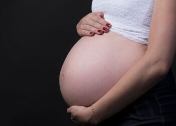 Imagem de uma gestante com a mão sobre a barriga, ilustrando o procedimento obrigatório para manter o Bolsa Família.