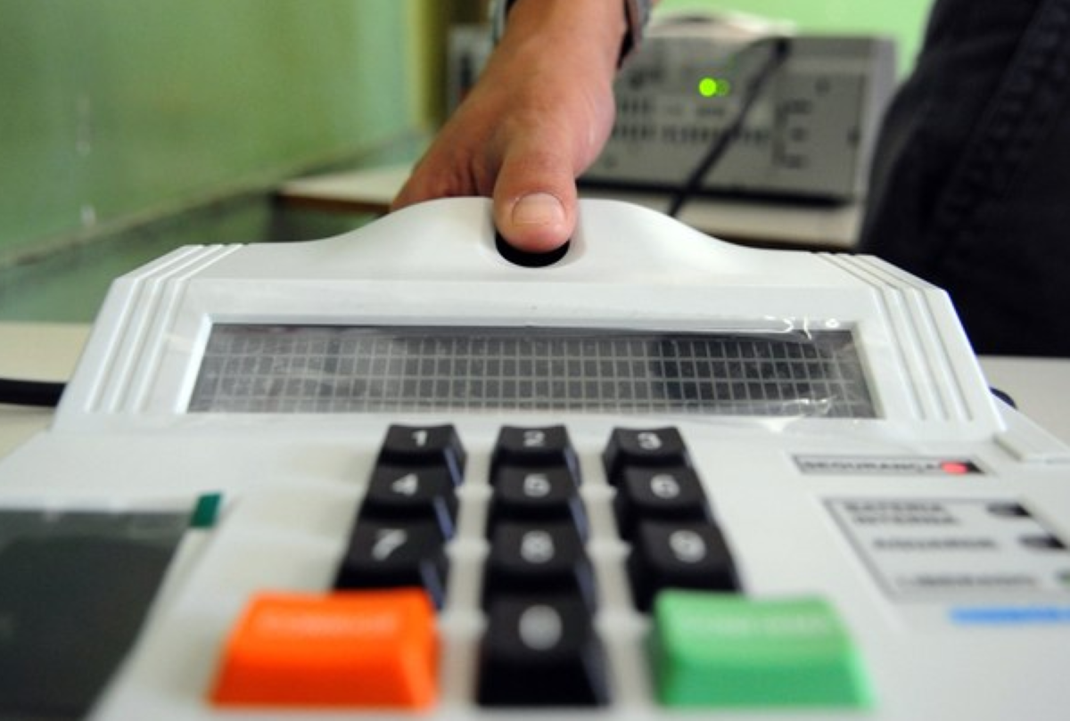 Pessoa utilizando leitor biométrico em equipamento eletrônico de cadastro.