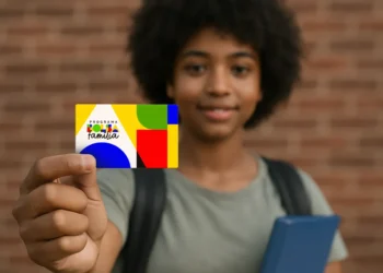 Jovem segurando cartão colorido do Programa Bolsa Família com foco no cartão.