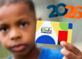 Criança segurando cartão amarelo com logo do Programa Bolsa Família e formas coloridas, com o número 2026 ao fundo.