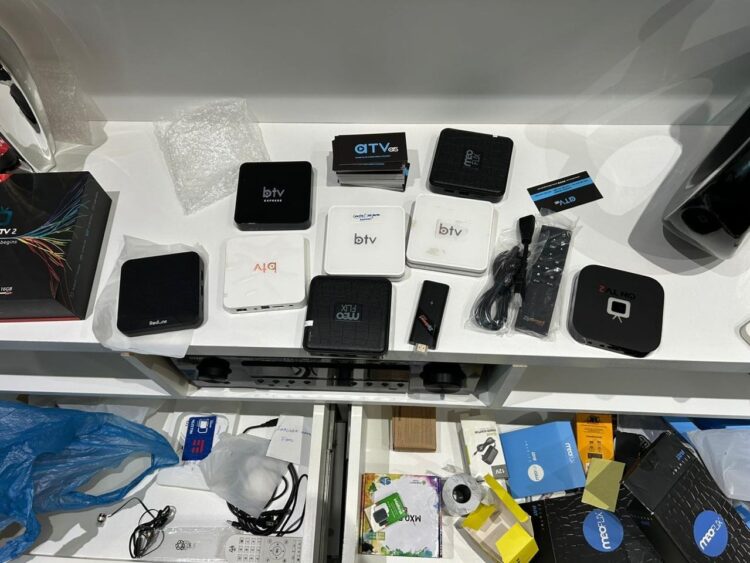 Vários modelos de TV Box, controles remotos, cabos e acessórios organizados sobre mesa branca