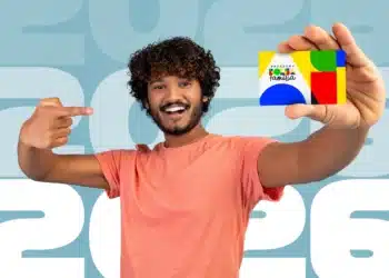 Isenção em concursos públicos para beneficiários do Bolsa Família: veja como 5 Homem sorridente segurando o cartão do Programa Bolsa Família, com fundo azul e ano de 2026.