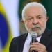 Presidente Lula diz que salário mínimo de R$ 1.621 é baixo e quer novo aumento 11 Lula discursando em evento com bandeira do Brasil ao fundo.