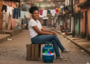 Mensagem "cadastro não cumpre regras" gera reclamações entre beneficiários do Gás do Povo 8 Jovem sorridente sentada em uma rua de comunidade com um botijão de gás do programa "Gás do Povo" ao lado.