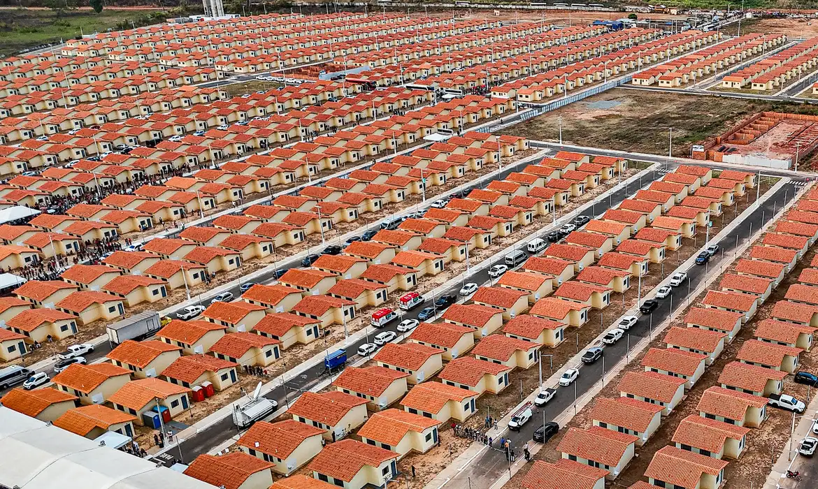 Conjunto habitacional popular do Minha Casa Minha Vida 2026 Vista aérea de milhares de casas populares do Minha Casa Minha Vida com telhados laranjas