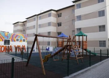 Playground em condomínio residencial do Minha Casa Minha Vida com prédio ao fundo