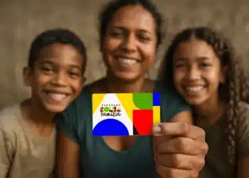 Bolsa Família: o que é verdade e o que é mentira sobre mudanças no pagamento em 2026 10 Mulher segura cartão colorido do Bolsa Família com duas crianças sorrindo ao fundo
