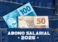 Abono Salarial 2026: descubra se você está entre os 25 milhões contemplados 11 Cédulas de R$ 100 e R$ 50 saindo de bolso de jeans com texto Abono Salarial 2026.