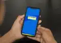 Pessoa segurando celular com aplicativo Cadastro Único aberto na tela.